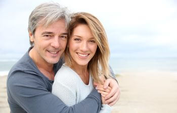 Cheerful mature couple with perfect smiles enjouying a walk along the beach.